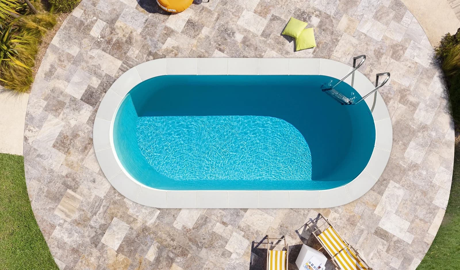 Kompakter ovaler Ilona-Pool aus der Luft mit heller Steinterrasse