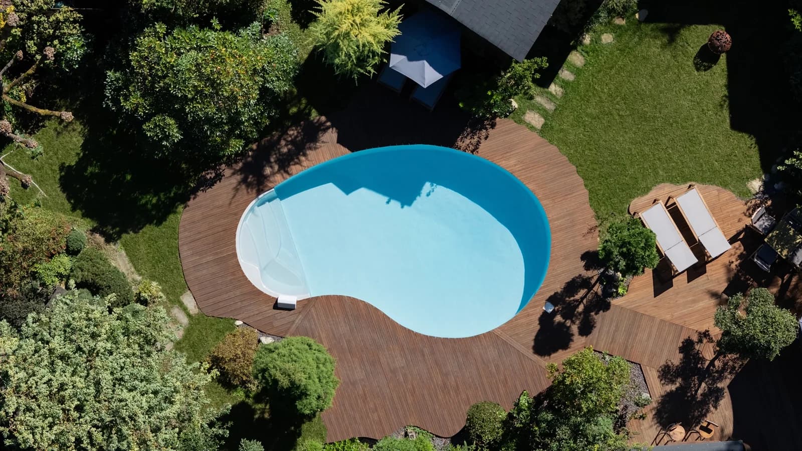Nierenförmiger Adele-Pool aus der Luft mit brauner Terrasse