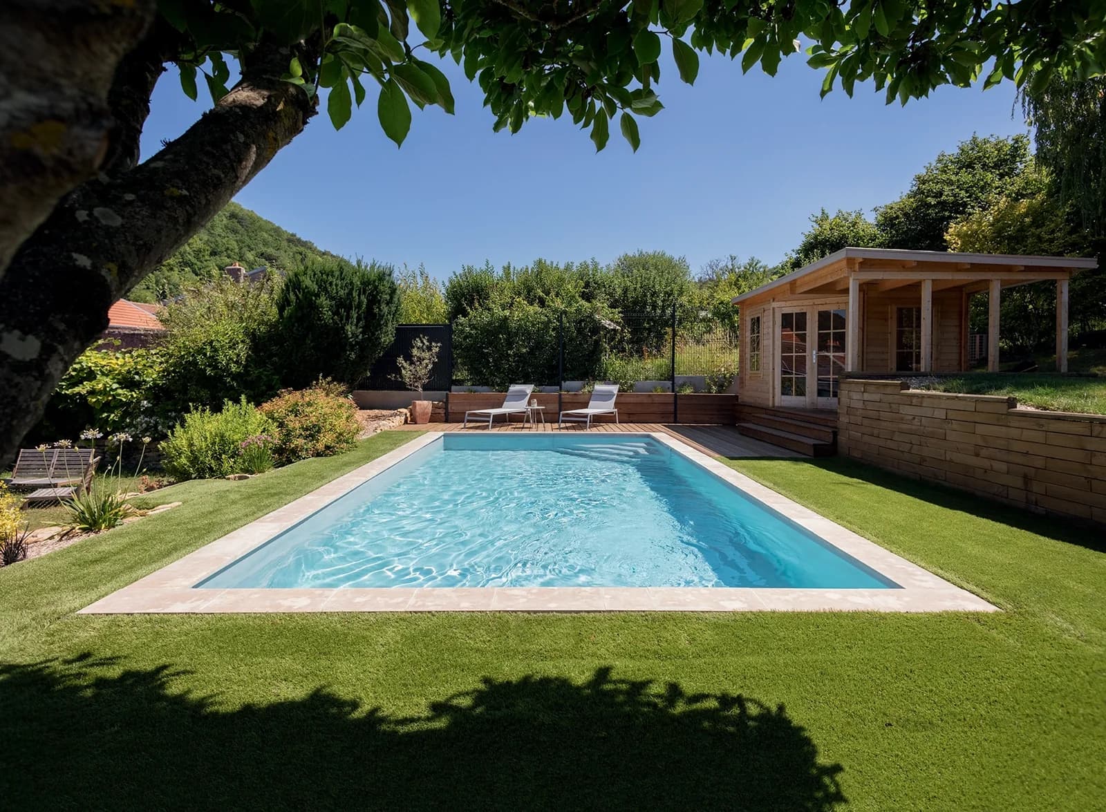 Tina-Pool mit heller Umrandung in einem grünen Garten