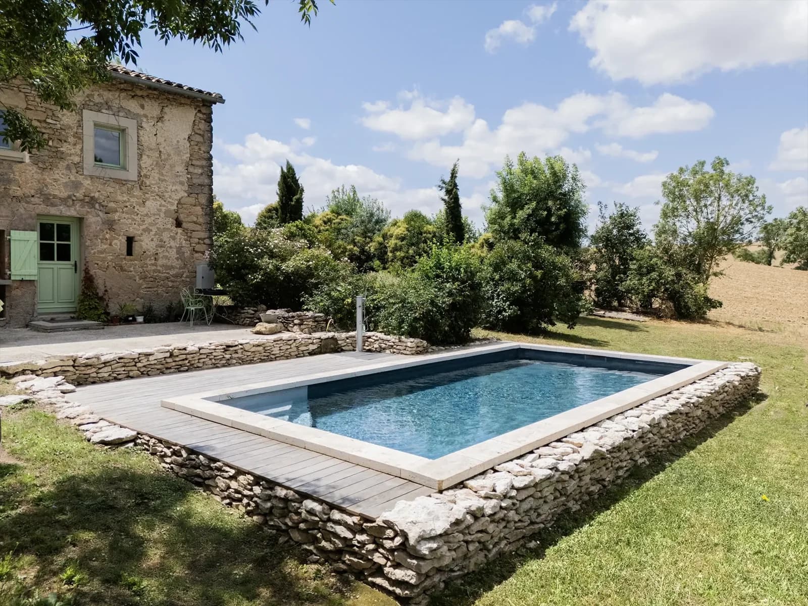 Tina-Pool mit Natursteinmauer an einem ländlichen Wohnhaus